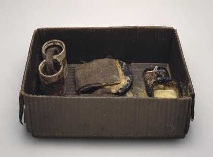 A brown box, open, with brown cylinders and other brown forms inside made of fat and felt, combined by Beuys to suggest the shape and function of a battery